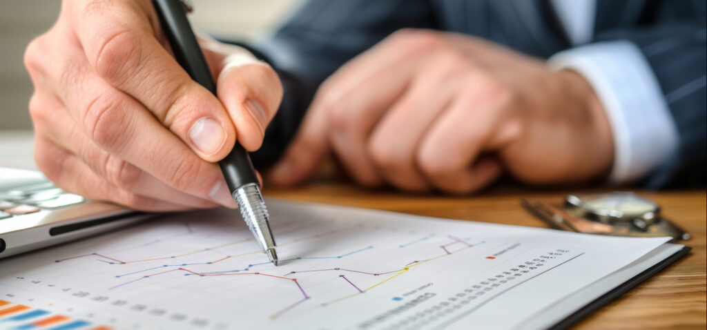 Widoczne ręce mężczyzny w garniturze, nanoszącego długopisem zmiany na wydrukowanym dokumencie